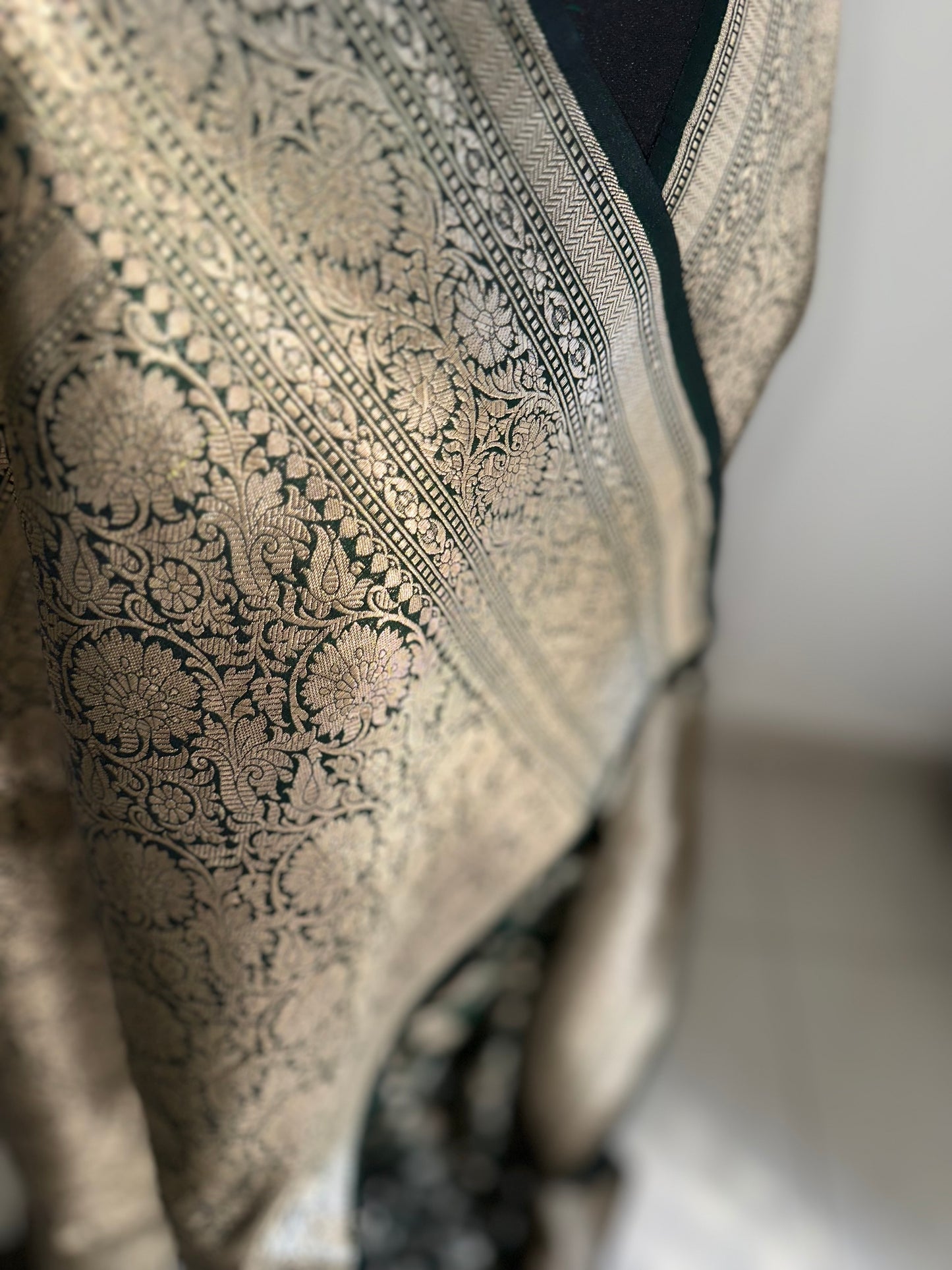 Elegant dark green pure silk Banarasi saree with intricate gold zari work and floral motifs, perfect for weddings and festive occasions