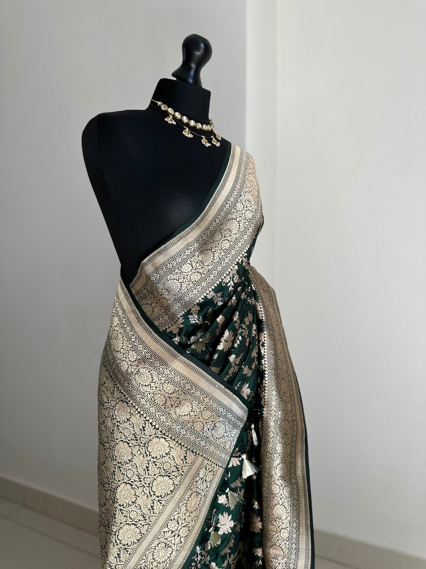 Elegant dark green pure silk Banarasi saree with intricate gold zari work and floral motifs, perfect for weddings and festive occasions