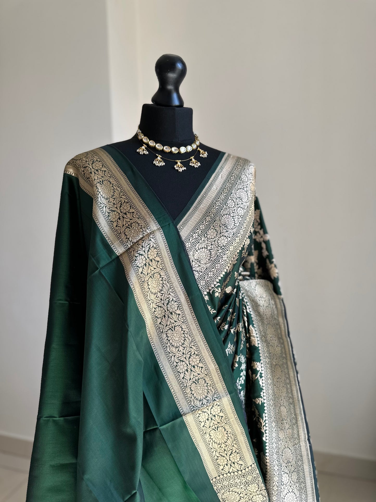 Elegant dark green pure silk Banarasi saree with intricate gold zari work and floral motifs, perfect for weddings and festive occasions