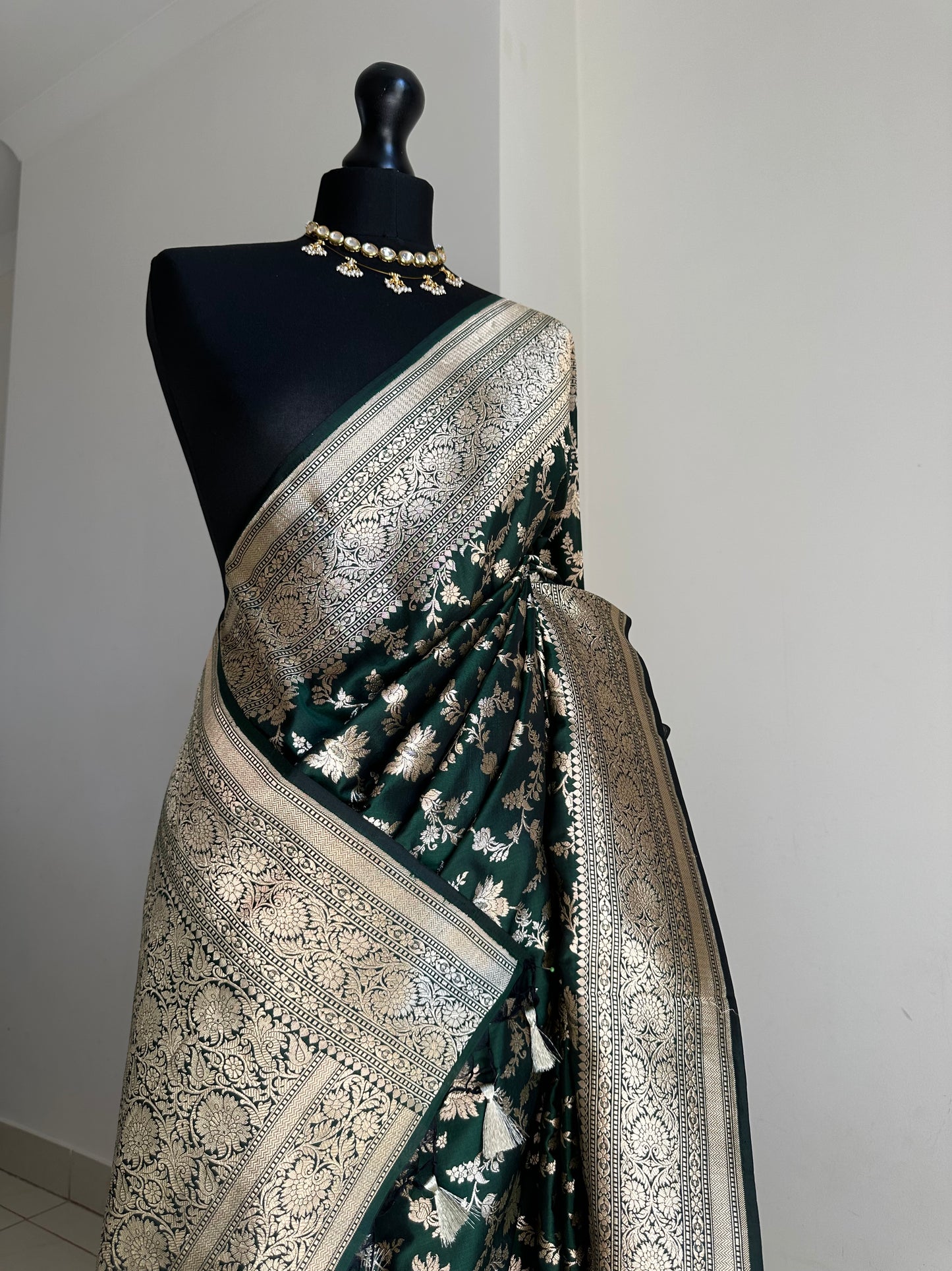 Elegant dark green pure silk Banarasi saree with intricate gold zari work and floral motifs, perfect for weddings and festive occasions