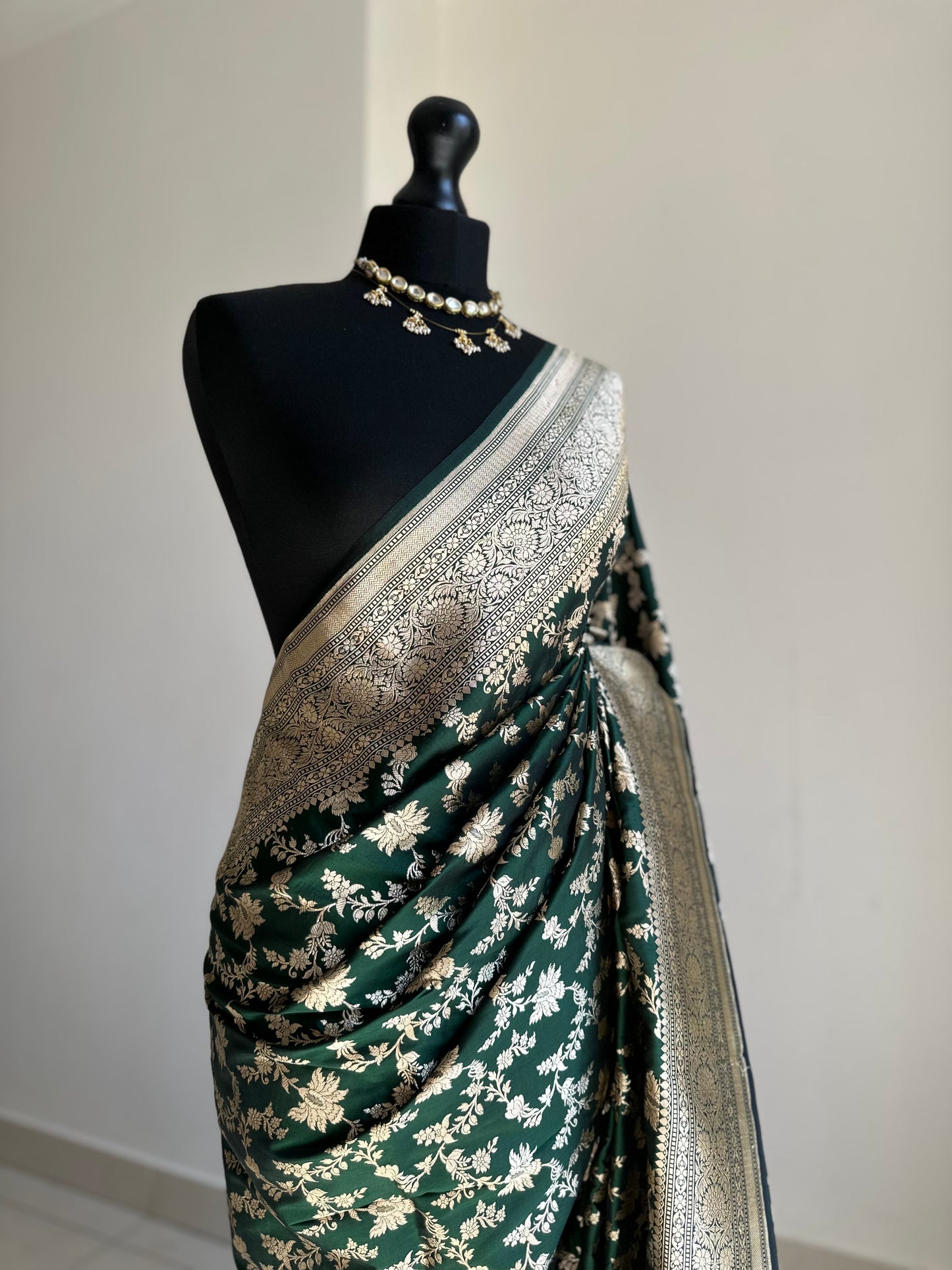 Elegant dark green pure silk Banarasi saree with intricate gold zari work and floral motifs, perfect for weddings and festive occasions