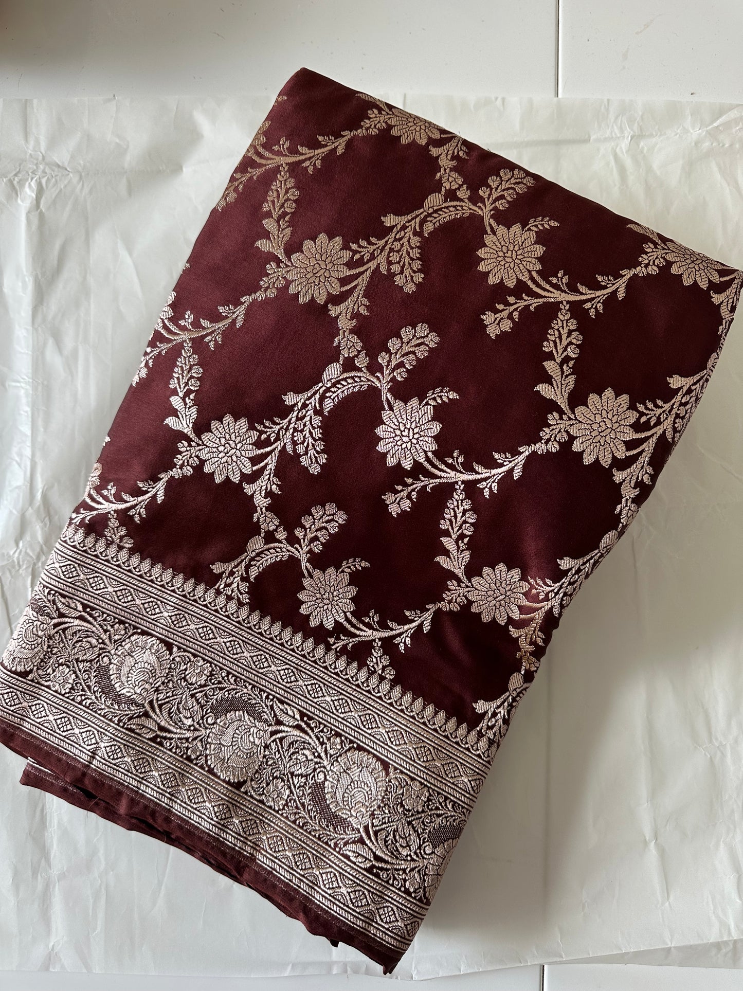Banarasi silk in dark chocolate brown with maroon hues gold zari. Gold and brown traditional wedding saree with jaal design and and plain contrast blouse with cuff border