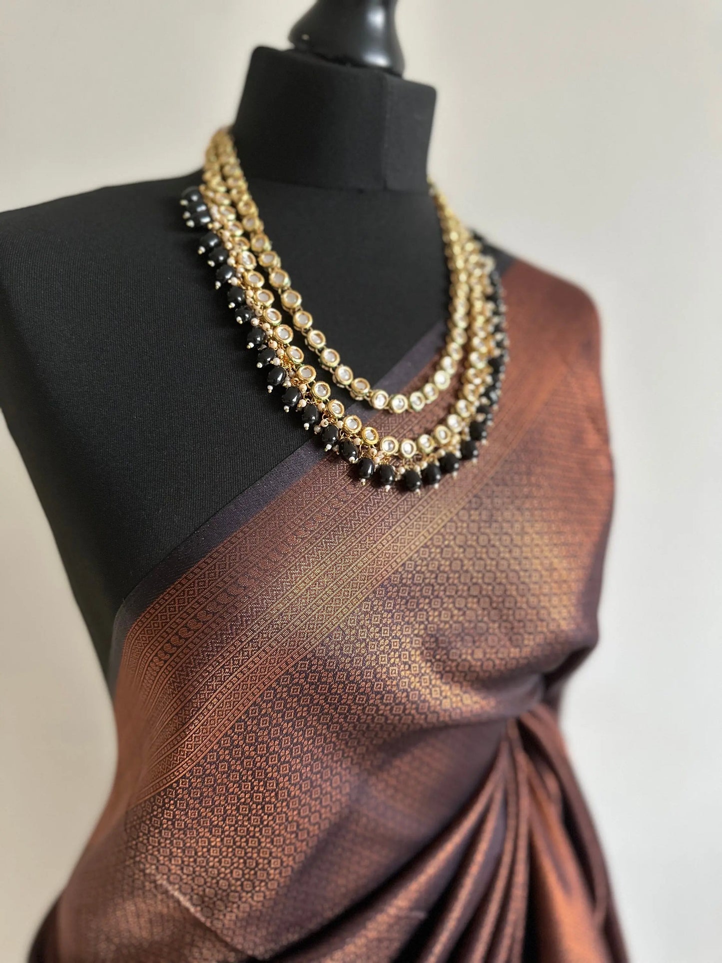 Black soft silk saree with a copper border and all over sheen. The perfect saree for parties and all traditional events. - LaiLai Sarees