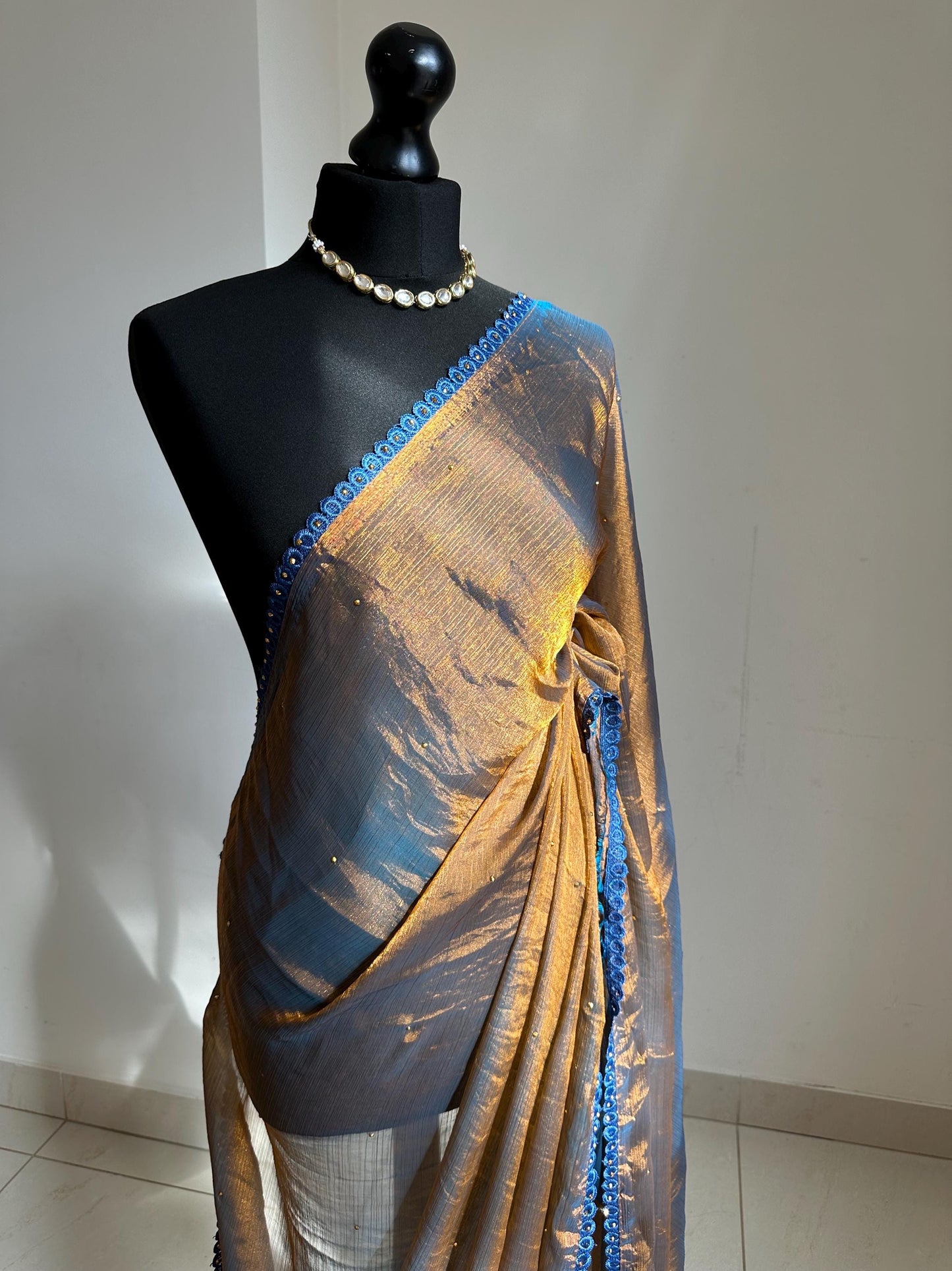 Dual toned gold party designer saree with blue trim border and contrast floral blouse. Unique statement saree can styled with other blouses