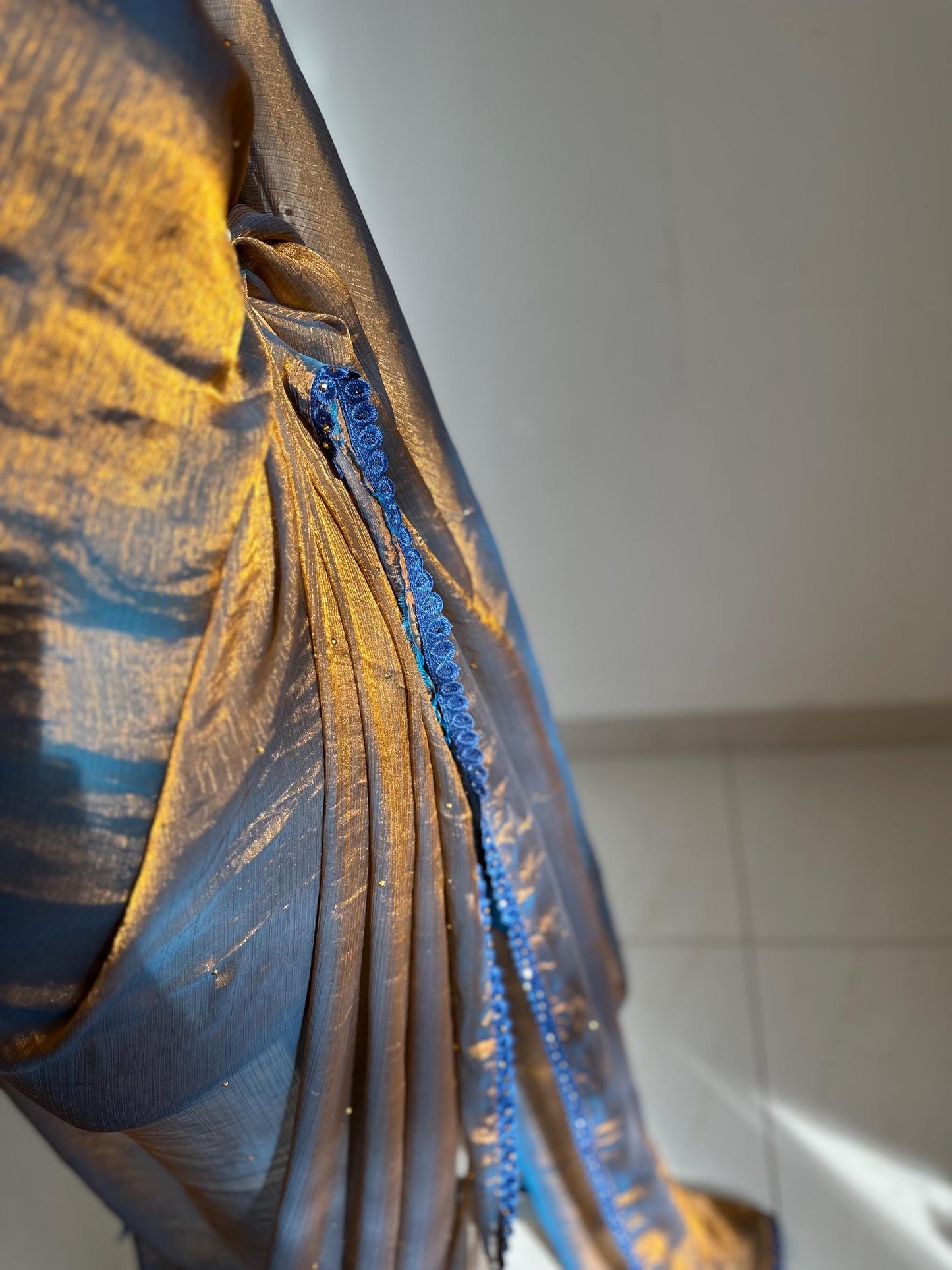 Dual toned gold party designer saree with blue trim border and contrast floral blouse. Unique statement saree can styled with other blouses