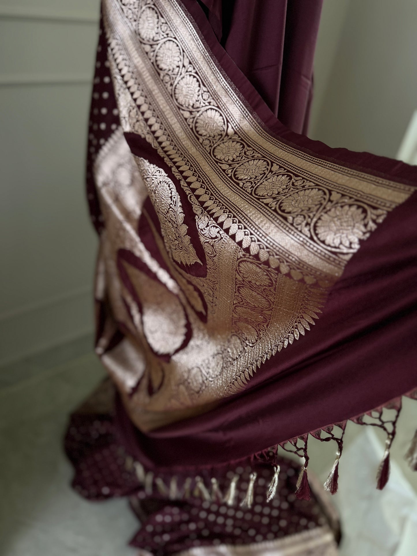Dark maroon Banarasi wedding saree with a hint of brown. Finished with elegant gold zari work, falls, picot and tassels.