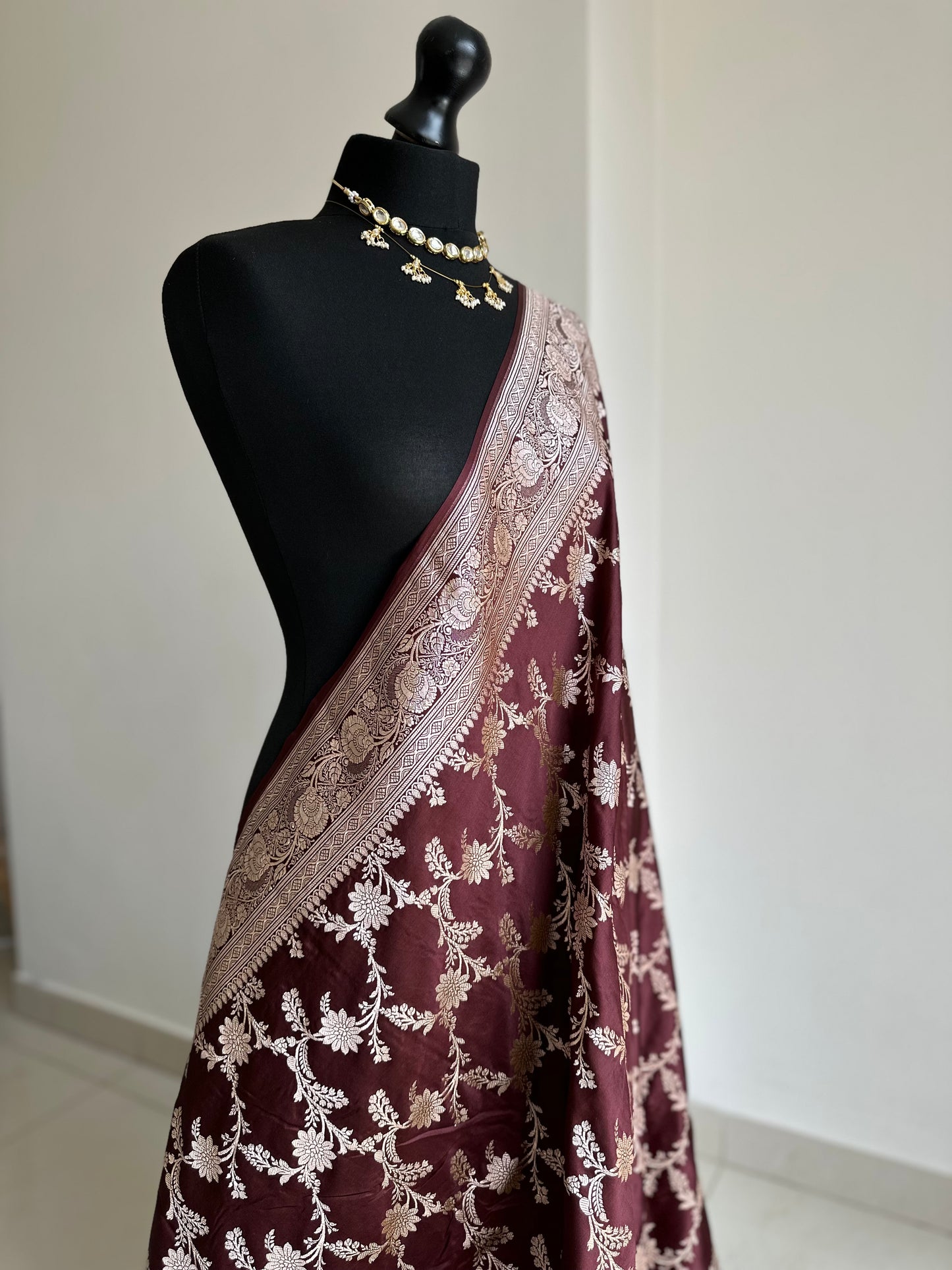 Banarasi silk in dark chocolate brown with maroon hues gold zari. Gold and brown traditional wedding saree with jaal design and and plain contrast blouse with cuff border