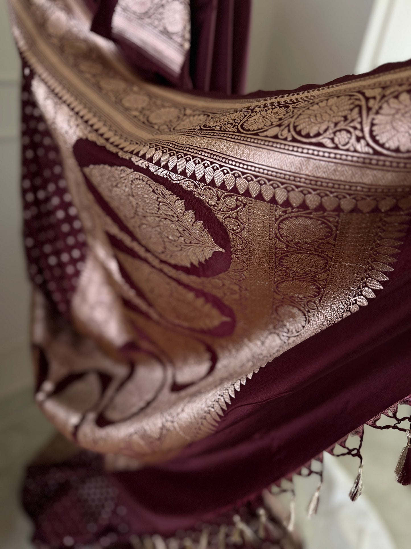 Dark maroon Banarasi wedding saree with a hint of brown. Finished with elegant gold zari work, falls, picot and tassels.