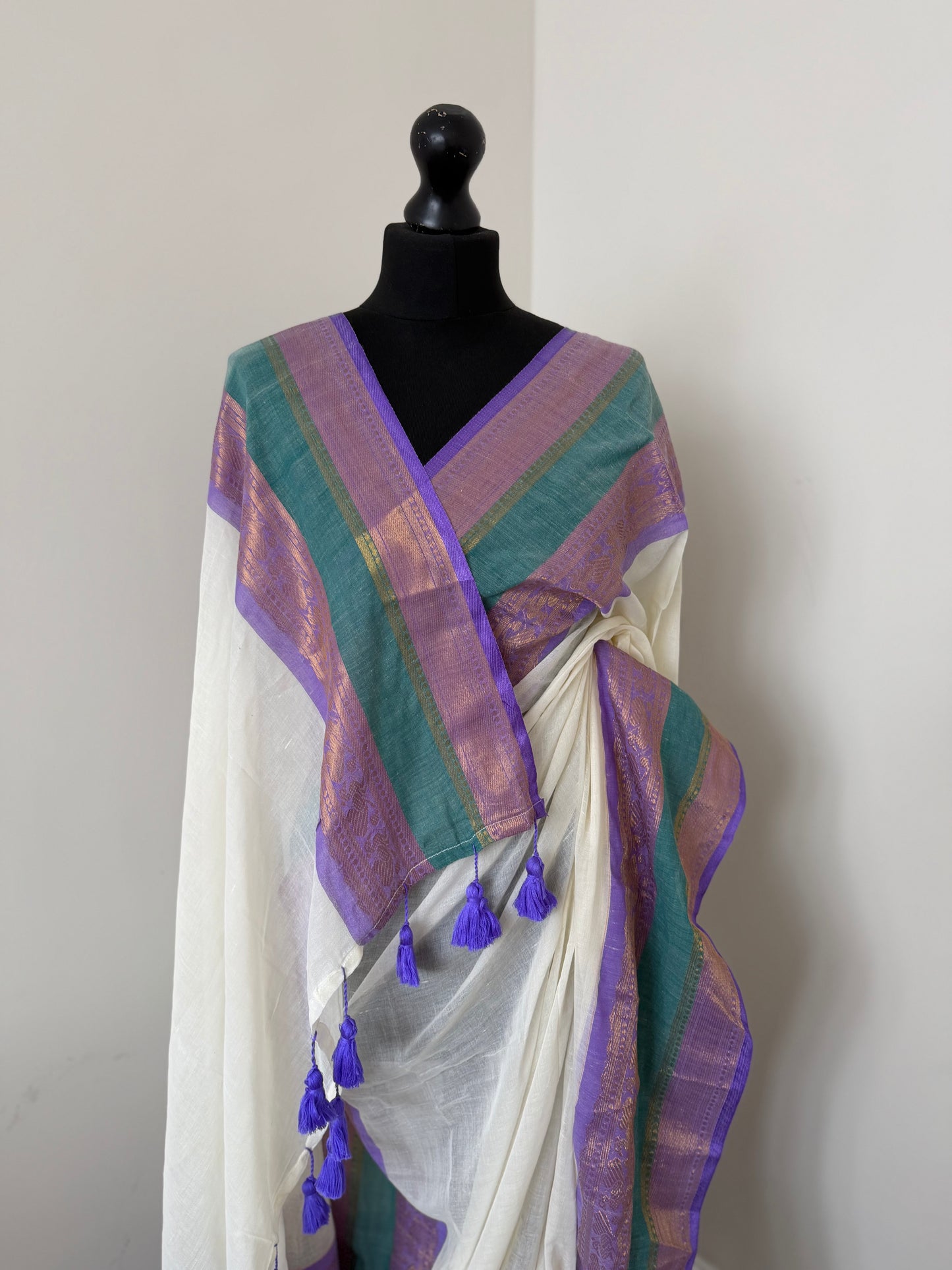 Elegant white pure mul cotton saree with purple and sea green border with gold zari weaving throughout.