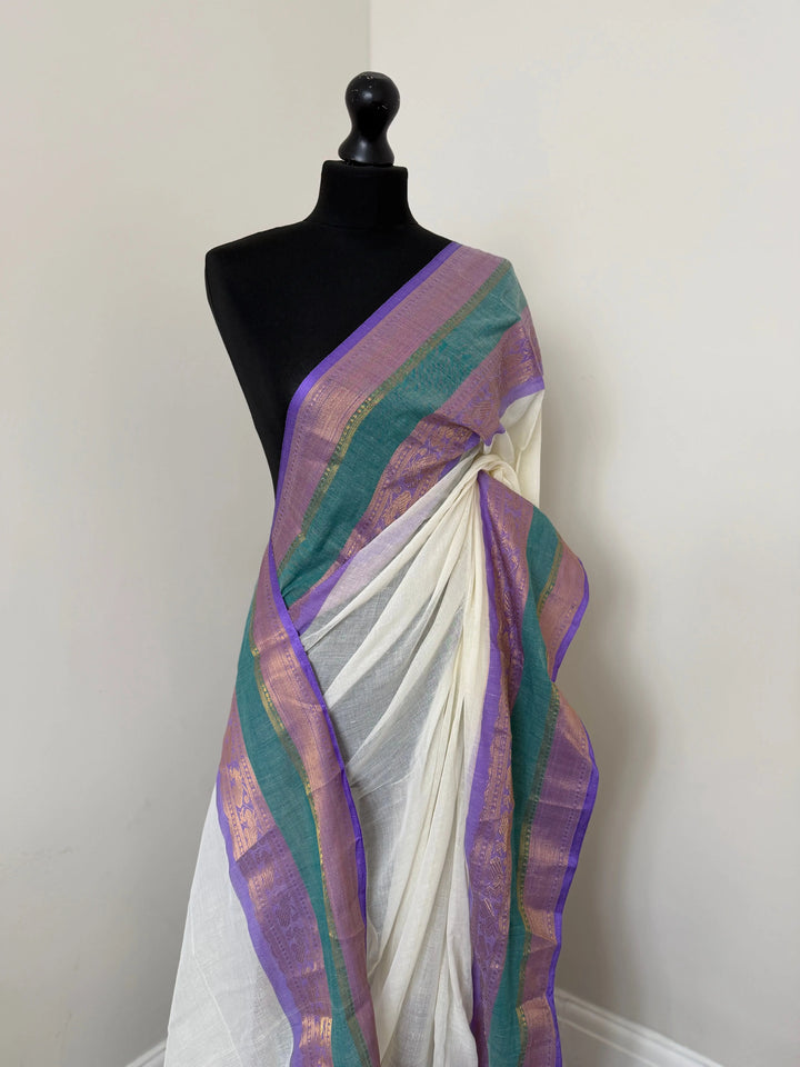 Elegant white pure mul cotton saree with purple and sea green border with gold zari weaving throughout. LaiLai Sarees