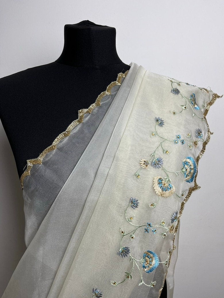 Dainty off white soft organza saree with stone work and pretty floral embroidery in shades of blue