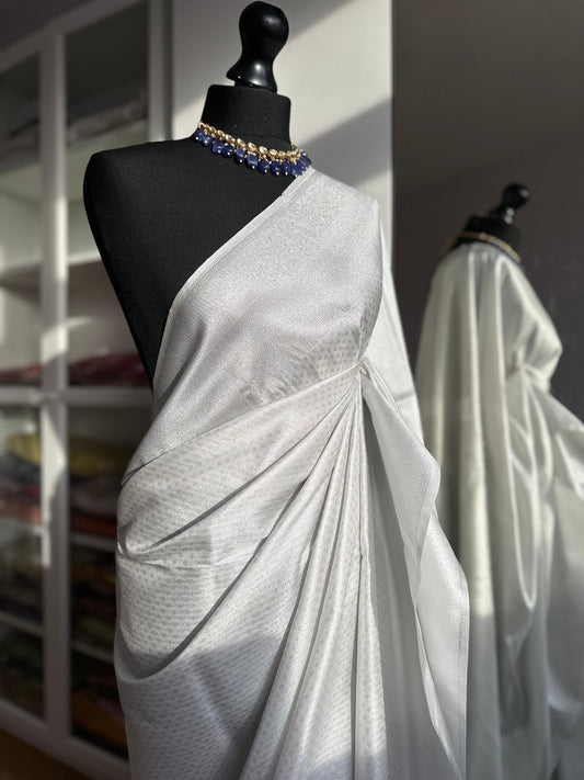 White and silver soft silk saree with an all over sheen. The perfect saree for parties and all traditional events. White saree for guests