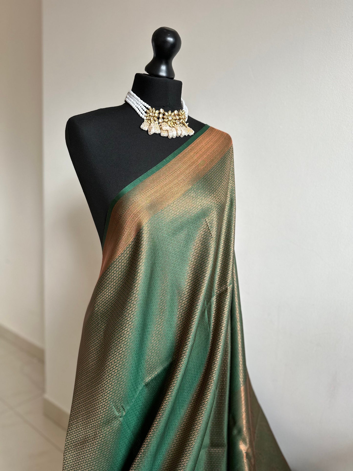 Bottle green silk saree with a copper border and all over sheen. The perfect saree for parties and all traditional events. Versatile saree