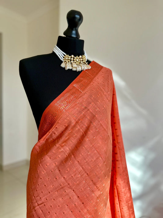 Orange coral soft tussar silk saree with border and unstitched blouse. Copper work all over and border. Statement saree and colour,stand out