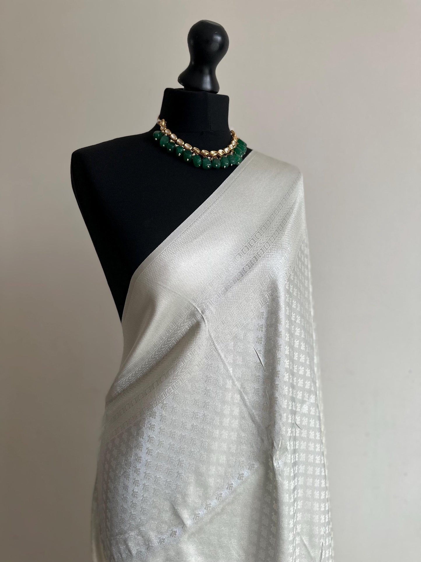 Off white and silver soft silk saree with an all over sheen. The perfect saree for parties and all traditional events.White saree for guests