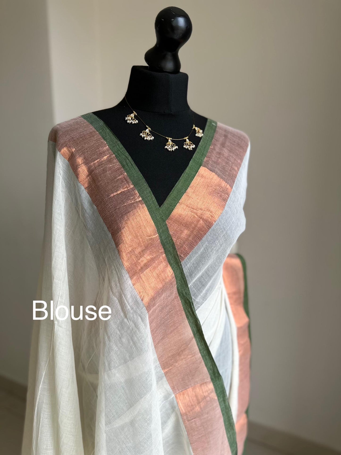 Elegant white mul cotton saree with copper zari border and green trim, lightweight handloom drape for festive and casual wear. Onam saree