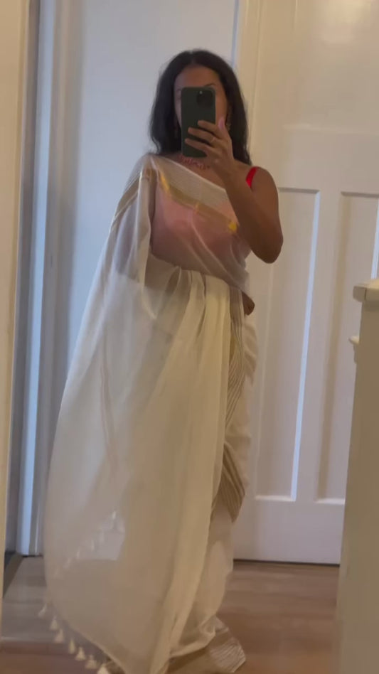 Elegant white pure mul cotton saree with gold zari border and tassels. Lightweight drape for festive and casual wear.